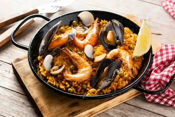 Pyszna paella z owocami morza, idealna do przygotowania z ryżem bomba. Krewetki, małże i cytryna dopełniają danie.