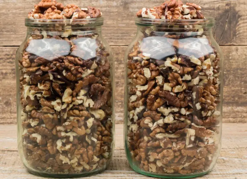 Dwa słoiki pełne łuskanych orzechów włoskich, idealne do przechowywania.